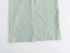 Detail of overlapping slit hem and mint green linen texture on minimalist summer dress