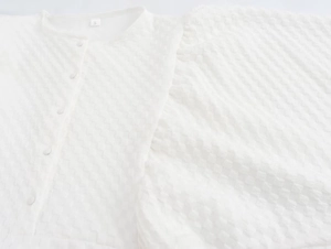 Detail of white seersucker fabric texture with round buttons and neckline on a summer dress