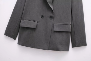 Detail of grey double-breasted blazer showing resin buttons and classic flap pockets