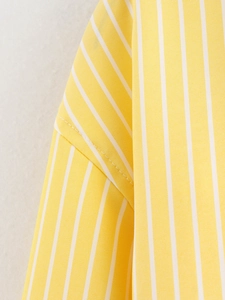 Close-up detail of neat stitching on yellow and white vertical striped shirt sleeves