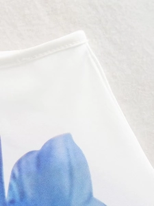 Macro detail of summer dress showing high-quality stitching and blue floral print on white fabric