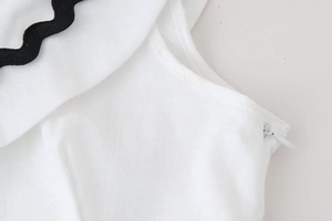 Close-up of cotton linen fabric texture with black wavy trim and invisible side zipper