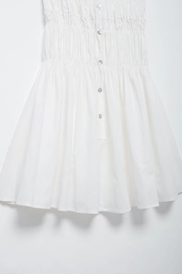 Detail of white summer mini dress featuring elegant ruched fabric and pearl buttons