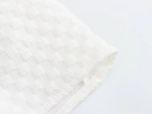 Detailed close-up of white seersucker fabric texture and clean ruffled edge stitching