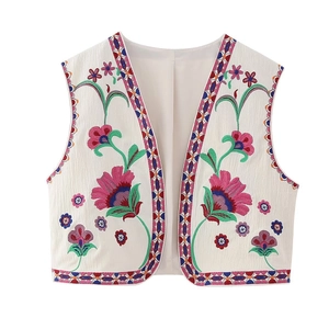 Gros plan d'une broderie florale ethnique colorée sur un gilet vintage sans manches crème