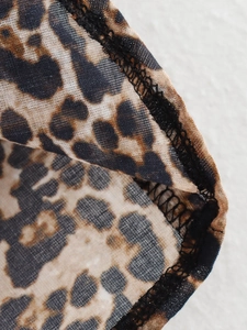 Macro detail of breathable leopard print mesh fabric with black overlock stitching edges