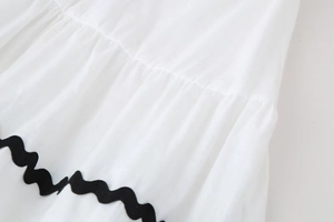 Detail of white cotton linen fabric with vertical texture and black wavy braided trim