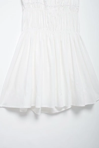 Close-up of white summer dress featuring detailed smocking waist and pleated texture