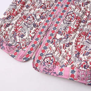 Detail of ethnic floral print on white quilted vest with a light purple zipper