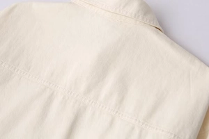 Detail view showing twill fabric texture and stitching of the beige cropped jacket