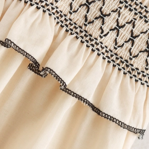 Chic beige midi dress featuring smocked chest detail with black embroidery and ruffled edges
