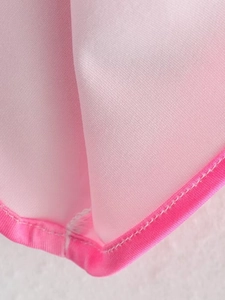 Close-up of pink printed dress fabric with clean edge stitching and fine diagonal texture