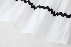 Detailed macro shot of white cotton-linen fabric with black ric rac wave trim details