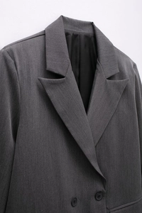 Detail of dark grey peak lapel with fine texture and resin buttons on blazer