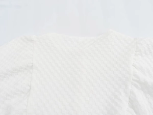 Detail of white puff-sleeve dress fabric featuring a textured checkered seersucker pattern