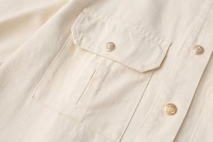 Detailed macro shot of twill cotton jacket fabric featuring a golden lion head button