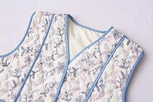 Detail of V-neck quilted vest with floral pattern and blue piping edge texture