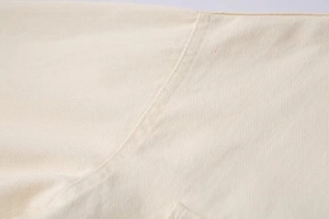 Detail of high-quality twill cotton fabric with neat stitching on a cream jacket