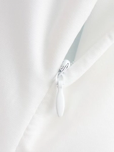 Detailed close-up of a white fabric dress featuring a hidden zipper and metal slider