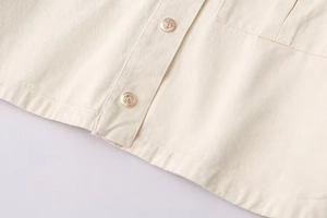 Detailed macro view of vintage gold embossed buttons on a beige twill cotton jacket
