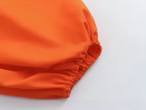 Close-up detail of the elastic ruffled cuffs on an exotic orange two-piece outfit