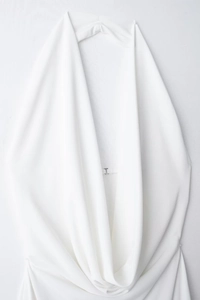 Detail of white halter neck dress featuring elegant ruched draping and a silver metal buckle