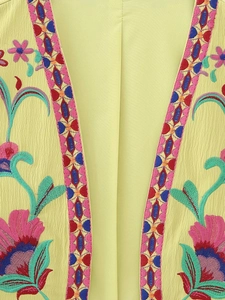 Détail du gilet jaune vif avec broderies ethniques fleuries et géométriques