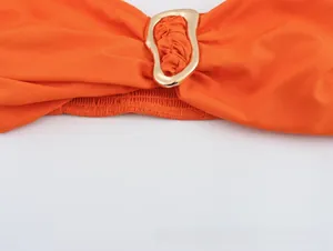 Detailed close-up of orange top with a central golden irregular metal ring buckle