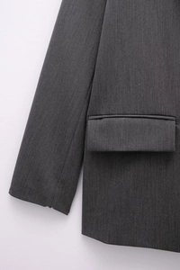 Detail of dark grey blazer showing flap pocket and premium twill fabric texture