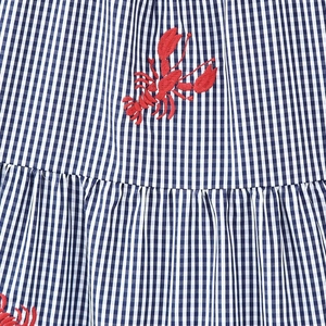 Blue and white gingham dress featuring intricate red lobster embroidery and pleated details