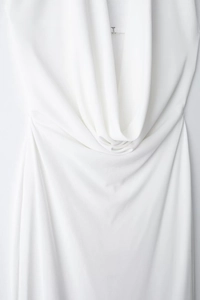 Detail of white cowl neck dress with elegant draped fabric and a silver metal J-buckle