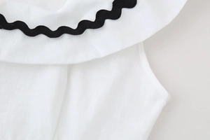 Macro shot of black wavy ricrack trim on white cotton-linen blend fabric detail