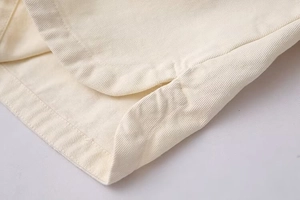 Close-up of beige twill cotton fabric with double-needle stitching and curved side slit