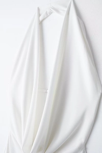 Detail of white halter neck dress with deep V-neck pleats and silver metal buckle