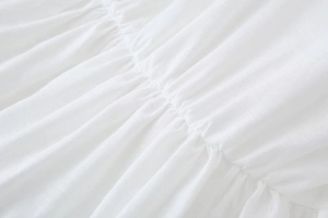 Macro view of white breathable linen-cotton fabric showing pleated texture and stitching