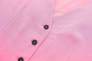 Detail of pink linen vest showing high-quality stitching and black round button closure