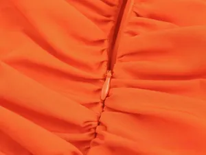 Detailed macro view of orange tube top with smooth zipper and fine pleated fabric detail