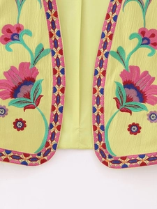 Détail de la broderie florale ethnique sur un gilet jaune vif ouvert pour femme
