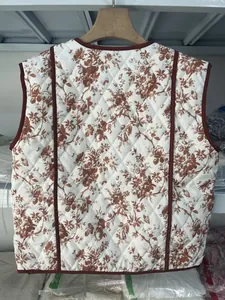 Detailed back view of a white quilted vest featuring vintage floral patterns and red piping