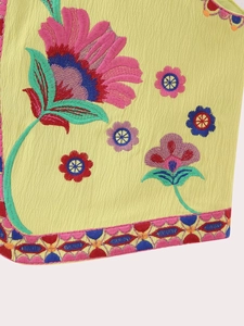 Détail de la broderie florale et du liseré géométrique sur ce gilet ethnique jaune