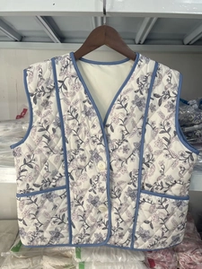 Detail of floral quilted vest with V-neck, blue binding, and white button closure