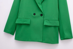 Detailed view of lime green double-breasted blazer with peaked lapels and flap pockets