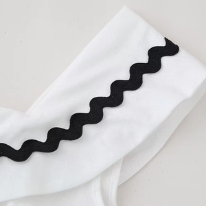 White cotton linen dress featuring decorative black ric rac wave trim on the fabric edge