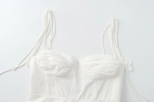 Detail of ruched bust and multiple spaghetti straps on a white slim-fit corset top