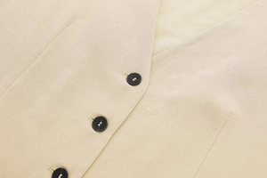 Detail view of beige linen vest featuring V-neckline and durable black resin buttons