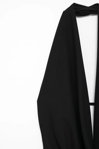 Detail view of black halter neckline with textured fabric and tie-back backless design