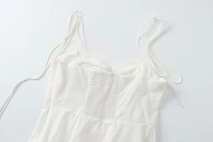 Detail of the white camisole top featuring thin straps and an elastic smocking back design