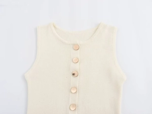 Close-up of cream knit sleeveless dress featuring elegant gold metal buttons and ribbed texture