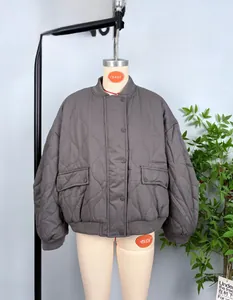 Detail view of grey-brown quilted bomber jacket with stand collar and flap pockets