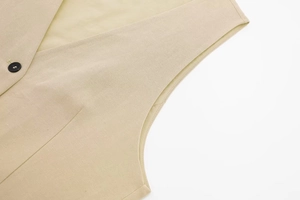 Close-up of linen V-neck vest showing natural fabric texture and black button detail